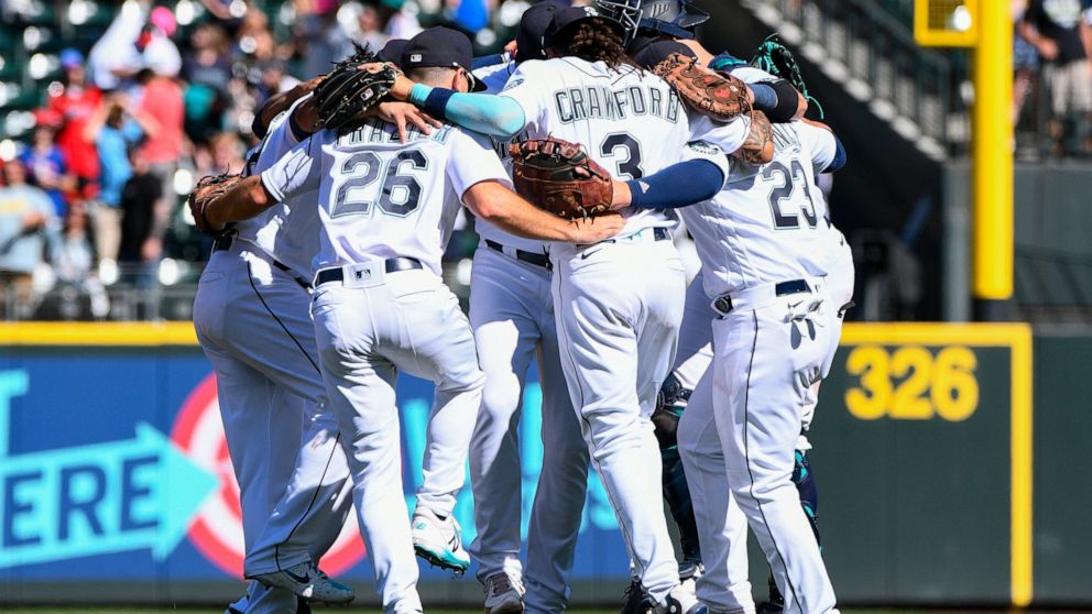 Seattle Mariners players celebrate with a group dance in center field after defeating the Los Angeles Angels in the first game of a baseball doubleheader, Saturday, Aug. 6, 2022, in Seattle. (AP Photo/Caean Couto)