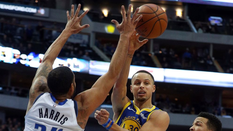 Golden State Warriors guard Stephen Curry (30) passes the ball around Dallas Mavericks guard Devin Harris (34) in the first half of an NBA basketball game Sunday, Jan. 13, 2019, in Dallas. (AP Photo/Richard W. Rodriguez)