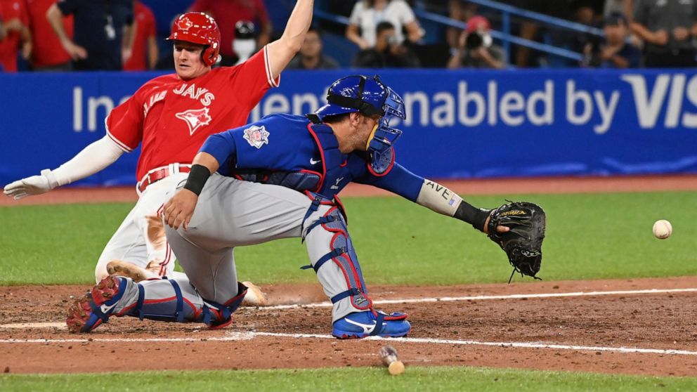 Toronto Blue Jays third baseman Matt Chapman, left, slides safely into home plate ahead of a tag by Chicago Cubs catcher Willson Contreras, right, on a walk-off single by Danny Jansen in the eleventh inning of a baseball game in Toronto on Monday, Au