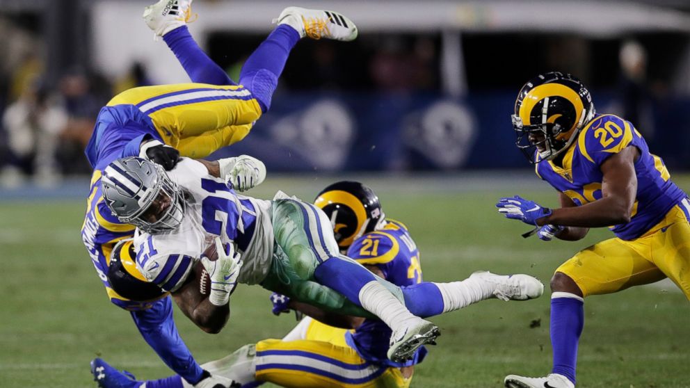 Dallas Cowboys running back Ezekiel Elliott is tackled by Los Angeles Rams linebacker Dante Fowler, top, and cornerback Aqib Talib during the second half in an NFL divisional football playoff game Saturday, Jan. 12, 2019, in Los Angeles. (AP Photo/Ja