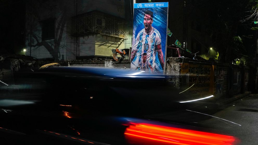 A car passes a poster of Argentina's Leonel Messi, erected by the Indian fans of Argentina during the World Cup semi final soccer match between Argentina and Croatia in Qatar, Wednesday, Dec. 14, 2022. Argentina defeated Croatia 3-0. (AP Photo/Bikas Das)