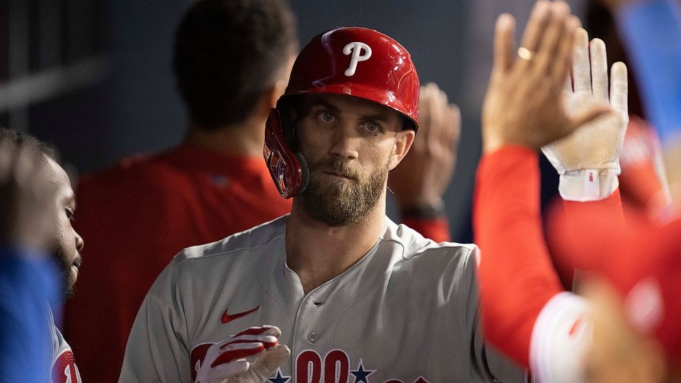 Philadelphia Phillies' Bryce Harper is greeted in the dugout after hitting an RBI sacrifice fly during the ninth inning of the team's baseball game against the Los Angeles Dodgers in Los Angeles, Thursday, May 12, 2022. (AP Photo/Kyusung Gong)