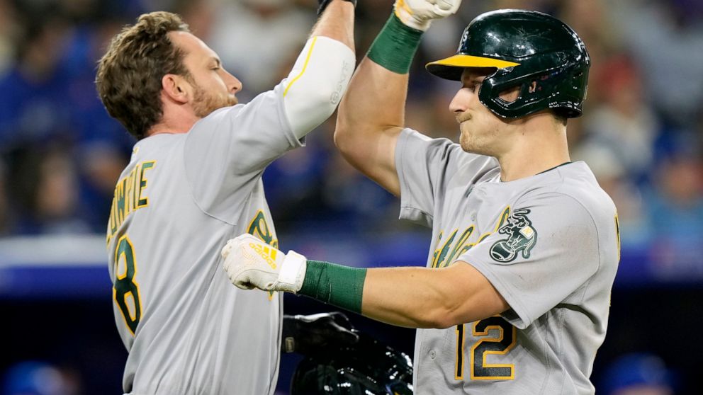 Oakland Athletics' Jed Lowrie (8) congratulates teammate Sean Murphy (12) on his two-run home run during third-inning baseball game action against the Toronto Blue Jays in Toronto, Saturday, April 16, 2022. (Frank Gunn/The Canadian Press via AP)