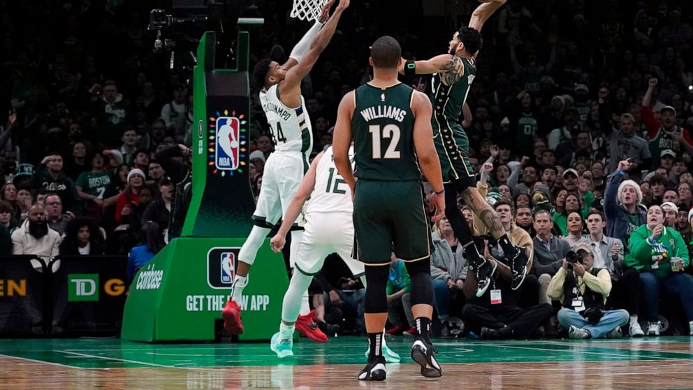 Boston Celtics forward Jayson Tatum (0) drives in for the slam dunk over Milwaukee Bucks forward Giannis Antetokounmpo (34) during the first half of an NBA basketball game, Sunday, Dec. 25, 2022, in Boston. (AP Photo/Mary Schwalm)