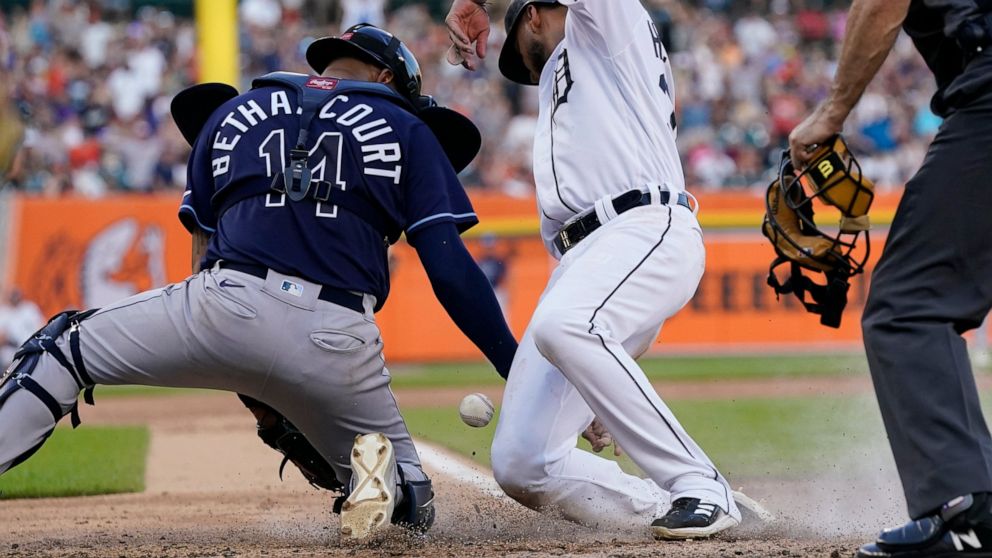 Tampa Bay Rays catcher Christian Bethancourt bobbles the throw from left fielder David Peralta as Detroit Tigers' Willi Castro scores during the fifth inning of a baseball game, Saturday, Aug. 6, 2022, in Detroit. (AP Photo/Carlos Osorio)