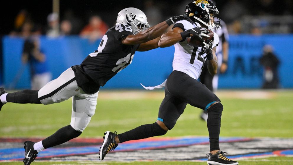 Jacksonville Jaguars wide receiver Marvin Hall (14) runs after a catch with Las Vegas Raiders cornerback Sam Webb (48) defending during the first half of the NFL football exhibition Hall of Fame Game, Thursday, Aug. 4, 2022, in Canton, Ohio. (AP Phot