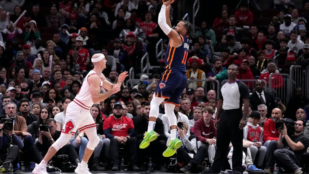 New York Knicks' Jalen Brunson (11) scores as Chicago Bulls' Alex Caruso watches in overtime of an NBA basketball game Wednesday, Dec. 14, 2022, in Chicago. The Knicks won 128-120. (AP Photo/Charles Rex Arbogast)