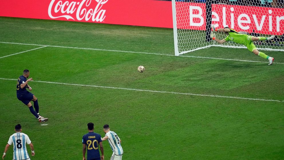 France's Kylian Mbappe shoots a free kick for his side's first goal during the World Cup final soccer match between Argentina and France at the Lusail Stadium in Lusail, Qatar, Sunday, Dec. 18, 2022. (AP Photo/Christophe Ena)