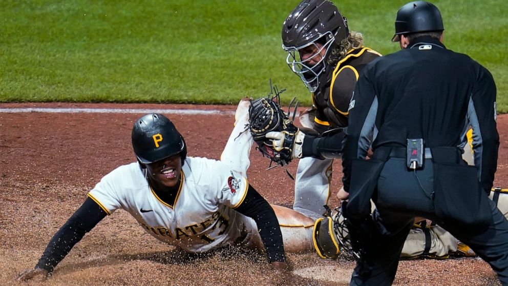 Pittsburgh Pirates' Ke'Bryan Hayes, left, scores the winning run past San Diego Padres catcher Jorge Alfaro, with umpire Mark Wegner watching during the 10th inning of a baseball game in Pittsburgh, Saturday, April 30, 2022. The Pirates won 7-6. (AP 
