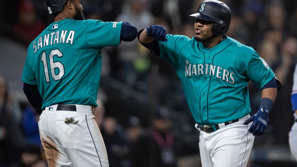 Seattle Mariners' Edwin Encarnacion, right, is congratulated by Domingo Santana after hitting a three-run home run off of Texas Rangers starting pitcher Shelby Miller that also scored Santana and Daniel Vogelbach during the third inning of a baseball