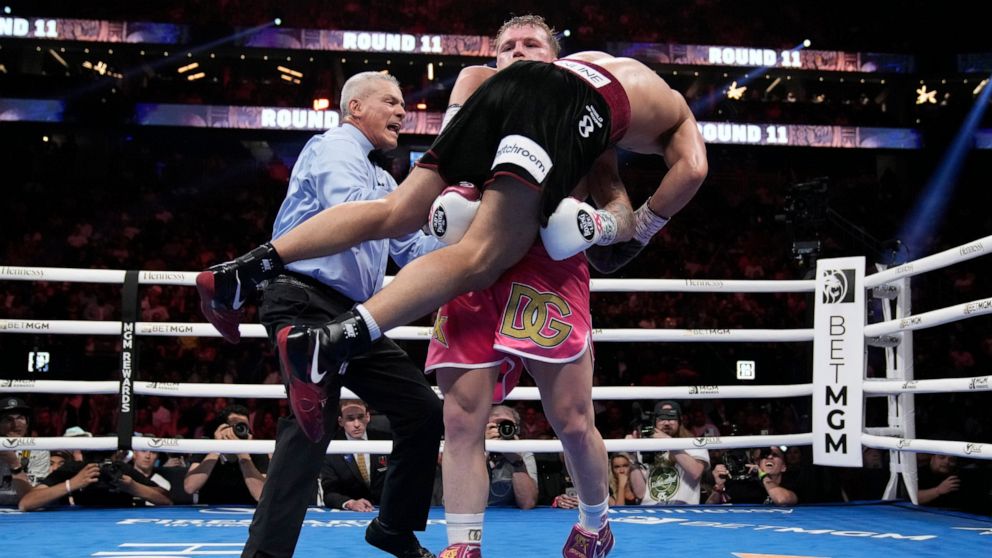Canelo Alvarez, of Mexico, lifts up Dmitry Bivol, of Kyrgyzstan, during a light heavyweight title fight, Saturday, May 7, 2022, in Las Vegas. (AP Photo/John Locher)