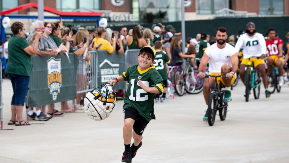 FILE - Green Bay Packers tight end Josiah Deguara, third from right, rides a young fan's bike as the fan takes off running with Deguara's helmet during the team's NFL football training camp July 27, 2022, in Green Bay, Wisc. (Samantha Madar/The Post-