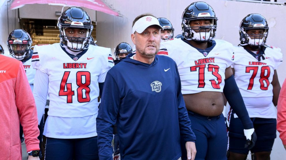 Liberty head coach Hugh Freeze, center, gets ready to take the field with his team to play Arkansas in an NCAA college football game Saturday, Nov. 5, 2022, in Fayetteville, Ark. (AP Photo/Michael Woods)