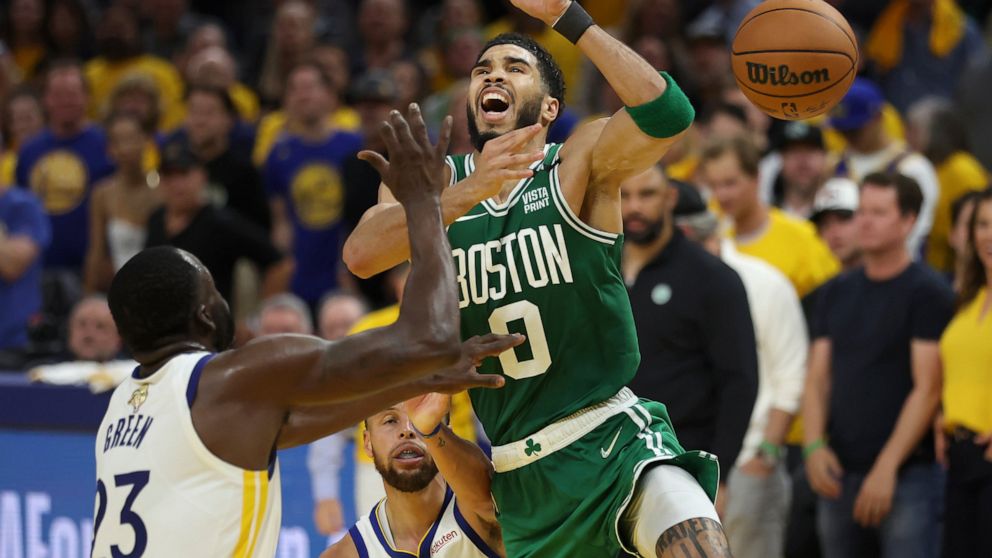 Boston Celtics forward Jayson Tatum (0) loses the ball while being defended by Golden State Warriors forward Draymond Green (23) and guard Stephen Curry during the second half of Game 1 of basketball's NBA Finals in San Francisco, Sunday, June 5, 202