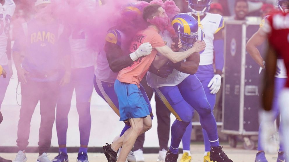 A protester is hit by Los Angeles Rams defensive end Takkarist McKinley, middle left, and linebacker Bobby Wagner during the first half of an NFL football game between the San Francisco 49ers and the Rams in Santa Clara, Calif., Monday, Oct. 3, 2022.