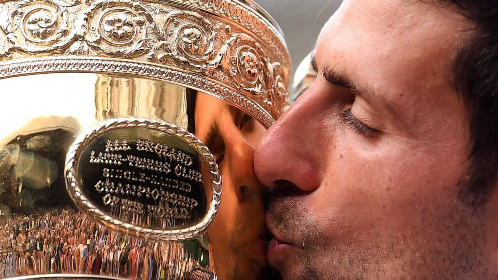 FILE - In this July 14, 2019, file photo, Serbia's Novak Djokovic kisses the trophy during the presentation after he defeated Switzerland's Roger Federer in the men's singles final match of the Wimbledon Tennis Championships in London. The All Englan