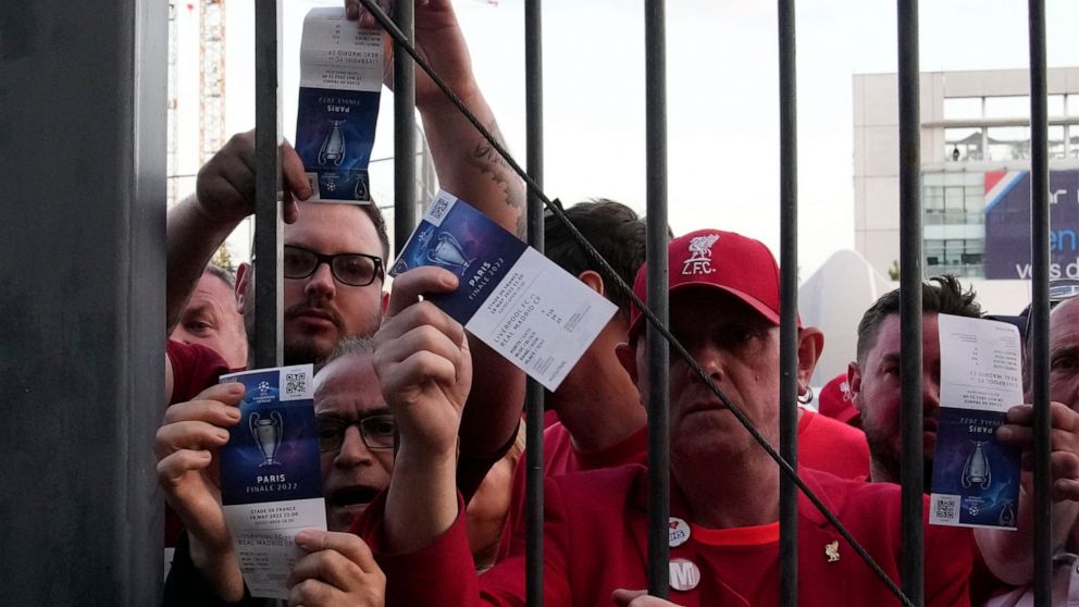 Fans shows tickets in front of the Stade de France prior the Champions League final soccer match between Liverpool and Real Madrid, in Saint Denis near Paris, Saturday, May 28, 2022. Police have deployed tear gas on supporters waiting in long lines t