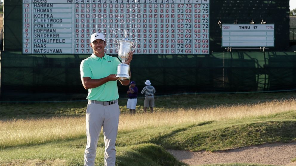 FILE - In this June 18, 2017, file photo, Brooks Koepka poses with the winning trophy after the U.S. Open golf tournament at Erin Hills in Erin, Wis. Koepka's victory was memorable for a record number of rounds under par and all the red on the leader