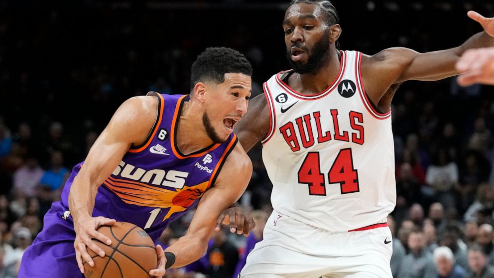 Phoenix Suns guard Devin Booker, left, drives past Chicago Bulls forward Patrick Williams (44) during the first half of an NBA basketball game in Phoenix, Wednesday, Nov. 30, 2022. (AP Photo/Ross D. Franklin)