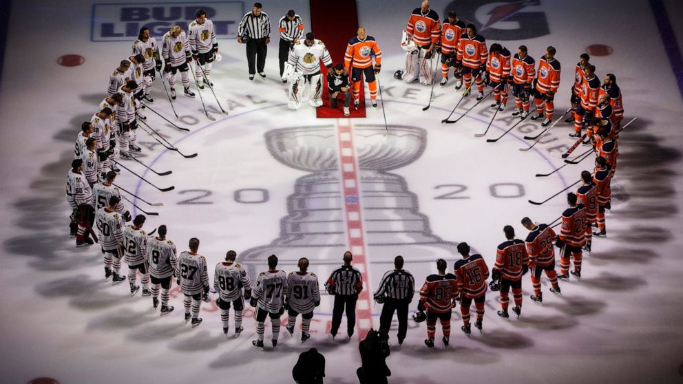 FILE - Minnesota Wild's Matt Dumba takes a knee during the national anthem flanked by Edmonton Oilers' Darnell Nurse, right, and Chicago Blackhawks' Malcolm Subban before an NHL hockey Stanley Cup playoff game in Edmonton, Alberta, Saturday, Aug. 1, 