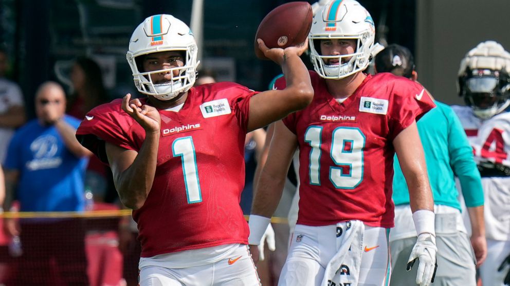 Miami Dolphins quarterback Tua Tagovailoa (1) throws a pass during an NFL football training camp practice with the Tampa Bay Buccaneers Wednesday, Aug. 10, 2022, in Tampa, Fla. Looking on is quarterback Skylar Thompson (19). (AP Photo/Chris O'Meara)