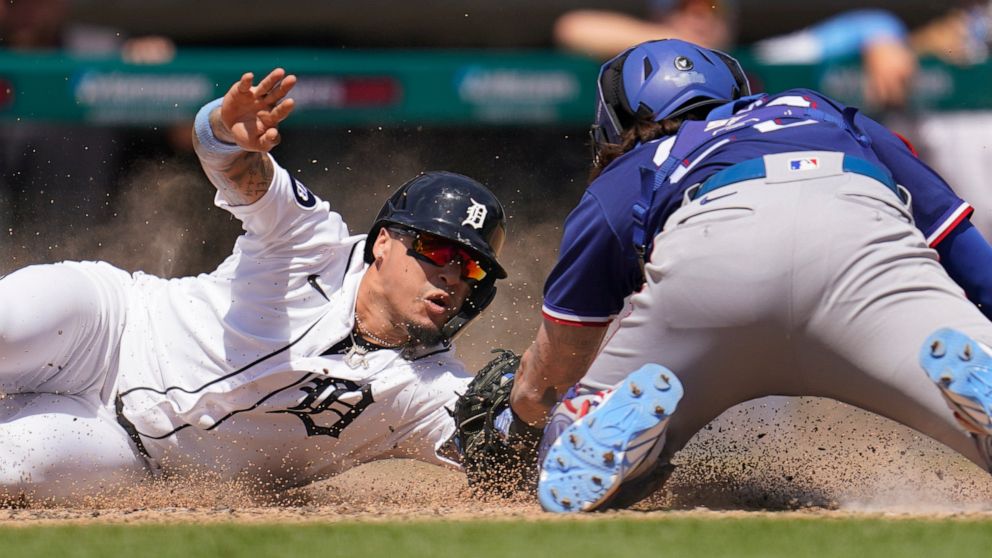 Detroit Tigers' Javier Baez slides safely to score ahead of the tag of Texas Rangers catcher Jonah Heim at home plate in the fifth inning of a baseball game in Detroit, Sunday, June 19, 2022. (AP Photo/Paul Sancya)
