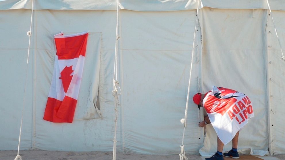 Canadian Modar Safar of Gilbert, Ontario ties closed his tent at a site in Al Khor, Qatar, Wednesday, Nov. 23, 2022. For scores of foreign soccer fans, the road to the World Cup in Doha starts every morning at a barren campsite in the middle of the d