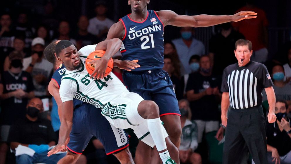 In a photo provided by Bahamas Visual Services, Michigan State forward Gabe Brown (44) falls to court after grabbing a rebound over Connecticut guard R.J. Cole, rear, and forward Adama Sanogo (21) during an NCAA college basketball game against Baylor