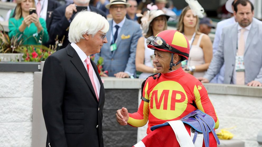 FILE - Jockey Mike Smith talks with trainer Bob Baffert after winning the Grade 2 Alysheba at Churchill Downs, Friday, May 3, 2019, in Louisville, Ky. The Kentucky Derby leads off the first Triple Crown season in decades without the chance of Bob Baf