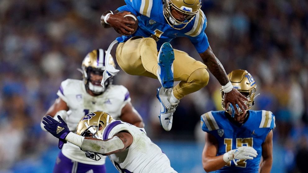UCLA quarterback Dorian Thompson-Robinson (1) leaps over Washington linebacker Kamren Fabiculanan during the first half of an NCAA college football game Friday, Sept. 30, 2022, in Pasadena, Calif. (AP Photo/Marcio Jose Sanchez)