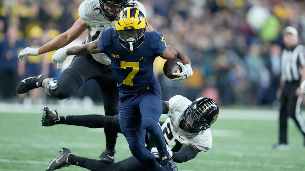 Michigan running back Donovan Edwards (7) runs with the ball as Purdue safety Sanoussi Kane (21) defends during the second half of the Big Ten championship NCAA college football game, Saturday, Dec. 3, 2022, in Indianapolis. (AP Photo/Michael Conroy)