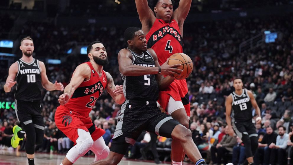 Sacramento Kings guard De'Aaron Fox (5) drives as Toronto Raptors guard Fred VanVleet (23) and forward Scottie Barnes (4) defend during the second half of an NBA basketball game in Toronto on Wednesday, Dec. 14, 2022. (Nathan Denette/The Canadian Pre