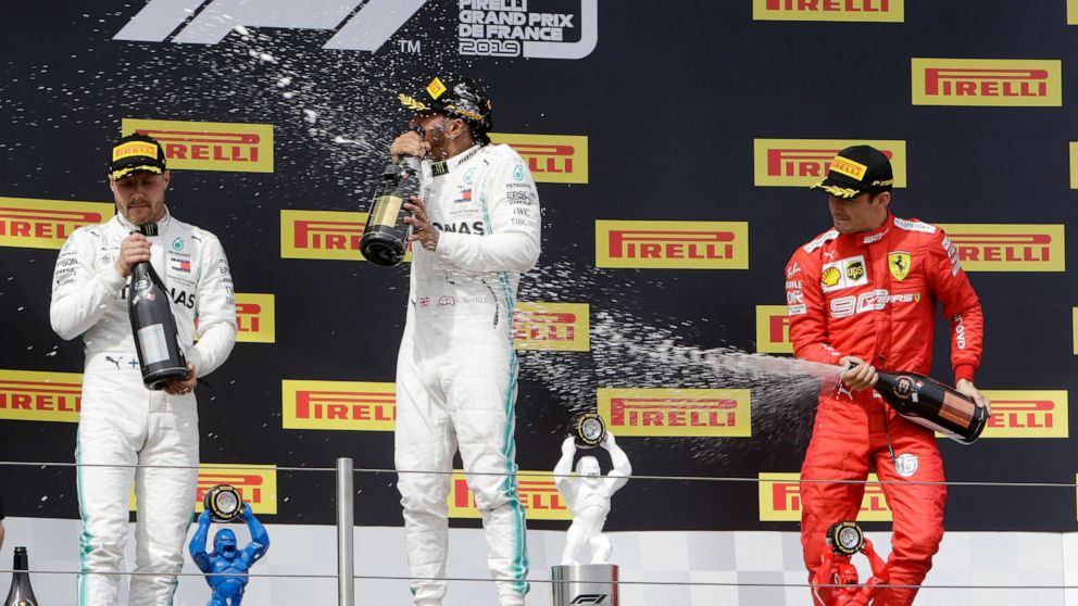 Mercedes driver Lewis Hamilton, center, of Britain, winner of the French Formula One Grand Prix, celebrates on the podium with second placed Mercedes driver Valtteri Bottas, left, of Finland, and third placed Ferrari driver Charles Leclerc, of Monaco