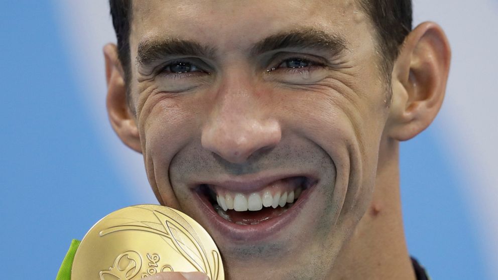 FILE - In this Aug. 9, 2016, file photo, Michael Phelps has tears in his eyes as he shows off his gold medal after the men's 200-meter butterfly final during the swimming competitions at the 2016 Summer Olympics, in Rio de Janeiro, Brazil. While swim