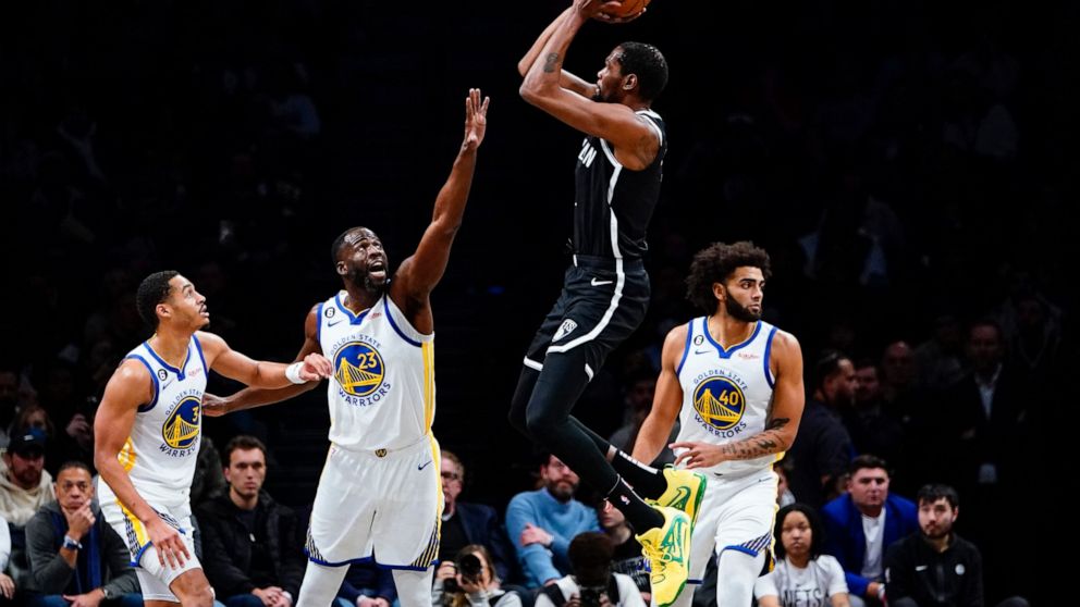 Golden State Warriors' Draymond Green (23) and Jordan Poole (3) defend a shot by Brooklyn Nets' Kevin Durant (7) during the first half of an NBA basketball game as teammate Anthony Lamb (40) watches Wednesday, Dec. 21, 2022 in New York. (AP Photo/Fra