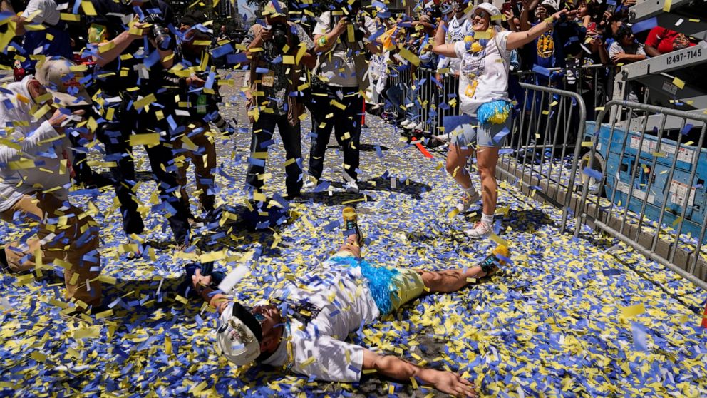 A man lays on Market Street as confetti rains during the Golden State Warriors NBA championship parade in San Francisco, Monday, June 20, 2022. (AP Photo/Eric Risberg)