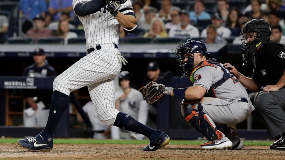 New York Yankees' Giancarlo Stanton follows through on a two-run single during the seventh inning of a baseball game as Houston Astros' catcher Max Stassi watches, Saturday, June 22, 2019, in New York. (AP Photo/Frank Franklin II)