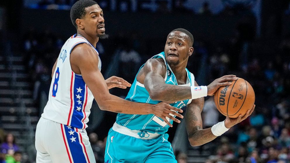 Charlotte Hornets guard Terry Rozier, right, looks to pass around the defense of Philadelphia 76ers guard De'Anthony Melton, left, during the first half of an NBA basketball game Wednesday, Nov. 23, 2022, in Charlotte, N.C. (AP Photo/Rusty Jones)