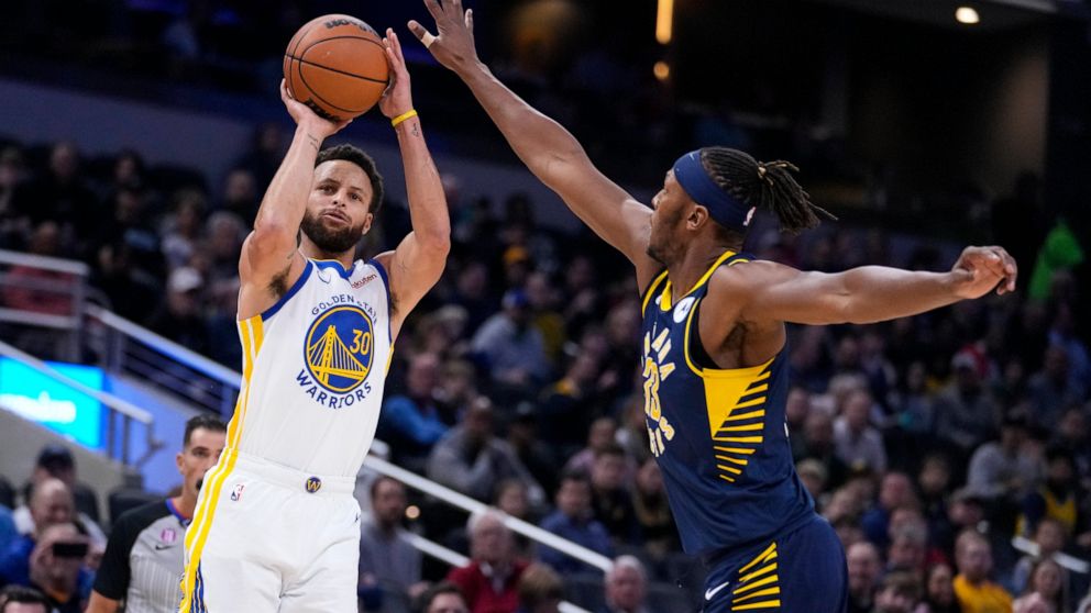 Golden State Warriors guard Stephen Curry (30) shoots over Indiana Pacers center Myles Turner (33) during the first half of an NBA basketball game in Indianapolis, Wednesday, Dec. 14, 2022. (AP Photo/Michael Conroy)