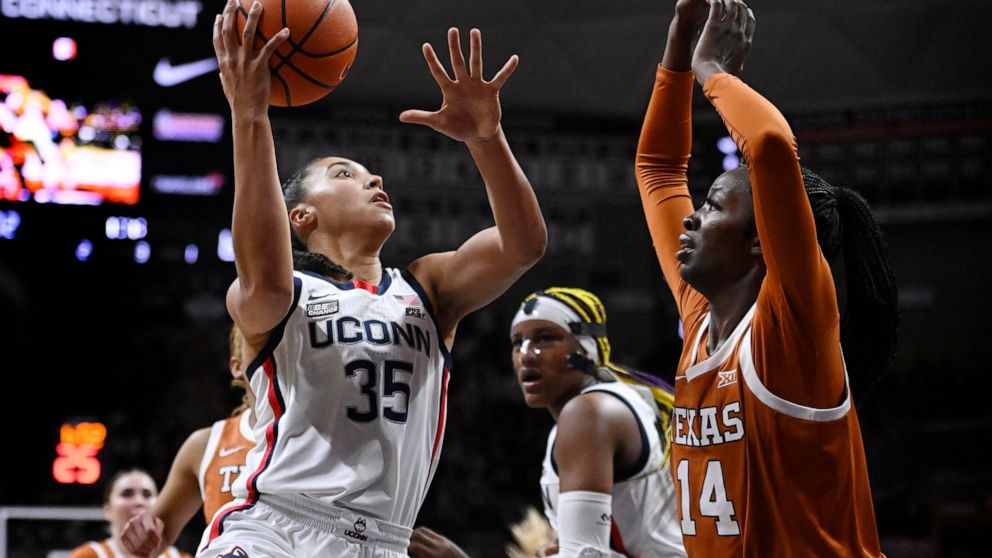 Connecticut's Azzi Fudd (35) shoots as Texas' Amina Muhammad (14) defends during the first half of an NCAA college basketball game, Monday, Nov. 14, 2022, in Storrs, Conn. (AP Photo/Jessica Hill)