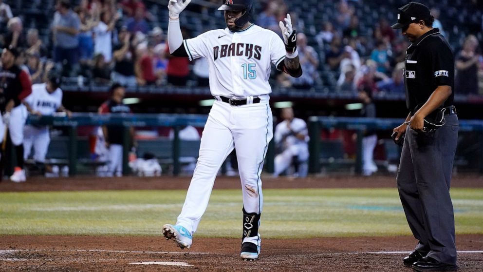 Arizona Diamondbacks' Emmanuel Rivera (15) celebrates as he arrives at home plate on his home run as umpire Erich Bacchus, right, looks on during the fourth inning of a baseball game Thursday, Aug. 11, 2022, in Phoenix. (AP Photo/Ross D. Franklin)