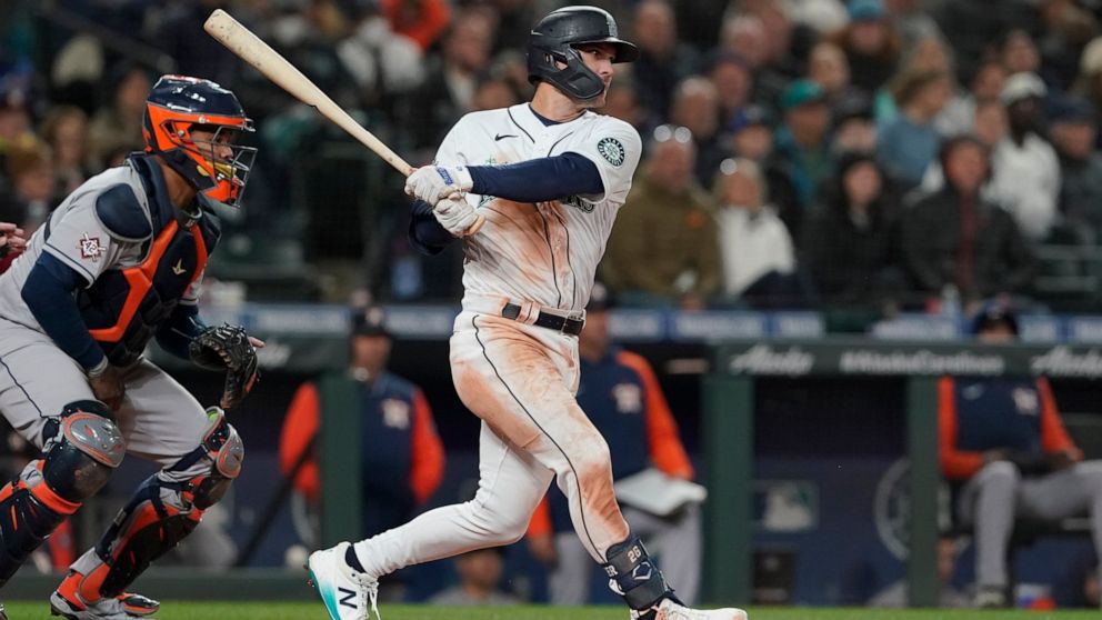 Seattle Mariners' Adam Frazier follows through on a single next to Houston Astros catcher Martin Maldonado during the sixth inning of a baseball game Friday, April 15, 2022, in Seattle. (AP Photo/Ted S. Warren)