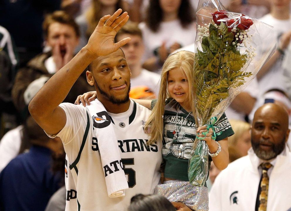 PHOTO: Adreian Payne walks on the floor for Senior night with Lacey Holsworth, a 8-year-old from St. Johns Michigan who is battling cancer in East Lansing, Mich., Feb. 6, 2014.