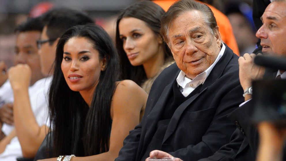 In this photo taken on Friday, Oct. 25, 2013, Los Angeles Clippers owner Donald Sterling, right, and V. Stiviano, left, watch the Clippers play the Sacramento Kings in Los Angeles. The NBA is investigating a report of an audio recording in which a man purported to be Sterling makes racist remarks while speaking to Stiviano.