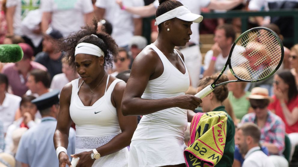 Serena and Venus Williams pass on the changeover during their match at the Wimbledon Championships in London, July 6, 2015.