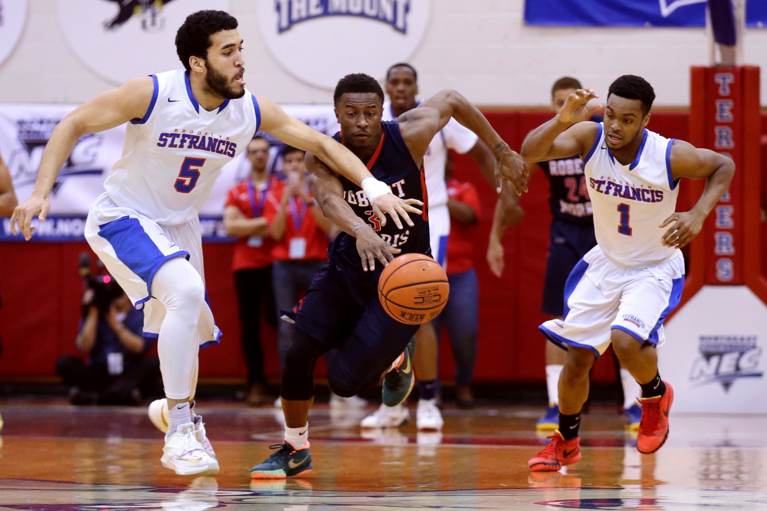 PHOTO: St. Francis forward Jalen Cannon (5) and guard Brent Jones (1) chase Robert Morris guard Kavon Stewart (3) during the first half of an NCAA college basketball game in the championship of the Northeast Conference tournament.