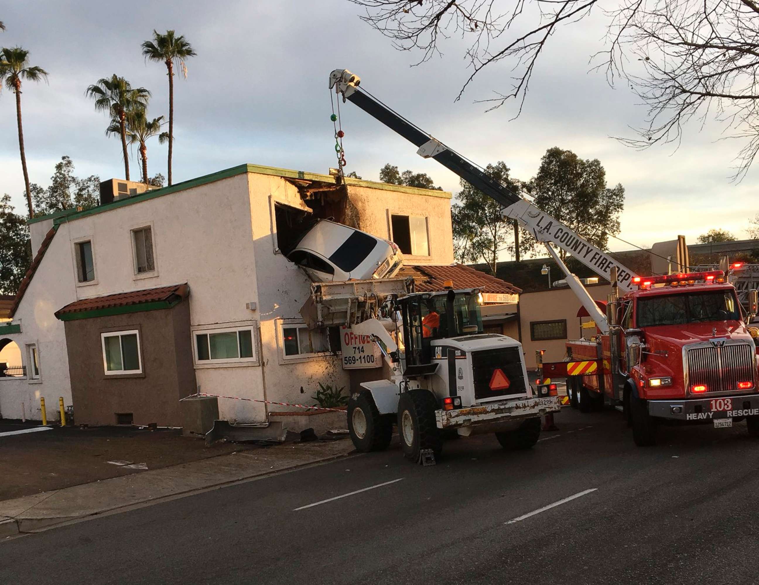 PHOTO: A crane is used to remove a vehicle hanging from a second story window after it hit a center divider and went airborne in Santa Ana, Calif., Jan. 14, 2018.