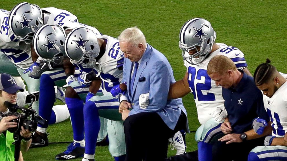 The Dallas Cowboys, led by owner Jerry Jones, center, take a knee prior to the national anthem prior to an NFL football game against the Arizona Cardinals, Sept. 25, 2017, in Glendale, Ariz.