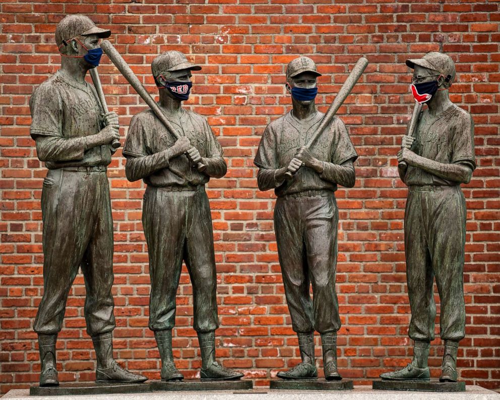 PHOTO: Statues of former Boston Red Sox players Ted Williams, Bobby Doerr, Johnny Pesky and Dom DiMaggio have been decorated with makeshift masks as the Major League Baseball season is postponed, April 9, 2020, at Fenway Park in Boston.