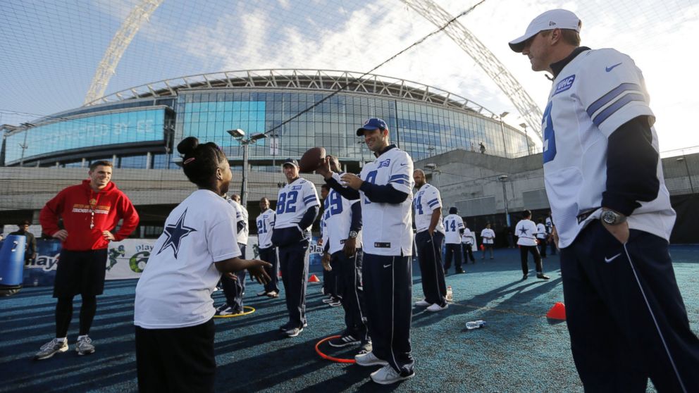 PHOTO: Dallas Cowboys quarterback Tony Romo (9) tosses a ball to a young player as the Dallas Cowboys help with a Play 60 event at the Power League soccer pitches outside Wembley Stadium, Nov. 4, 2014, in London.